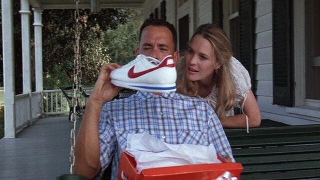Forrest Gump holding a pair of Nike running shoes.